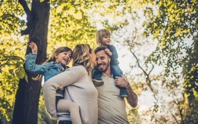 Parents carry two daughters on their shoulders in the park